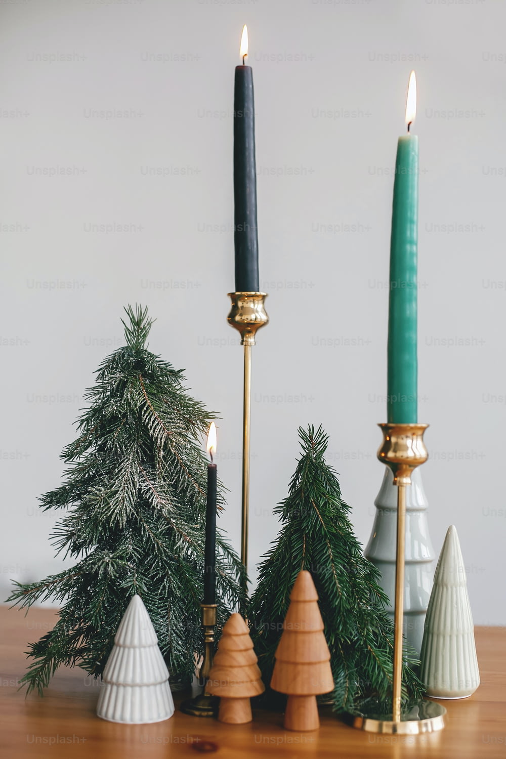 Christmas trees, candles and pine cones on rustic wooden table. Festive modern zero waste decor. Miniature wooden and handmade fir trees. Happy holidays