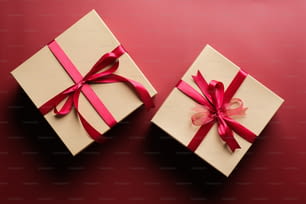 Gift boxes with red ribbon bow on marsala red background. Christmas present, valentine day surprise, birthday concept. Flat lay, top view.