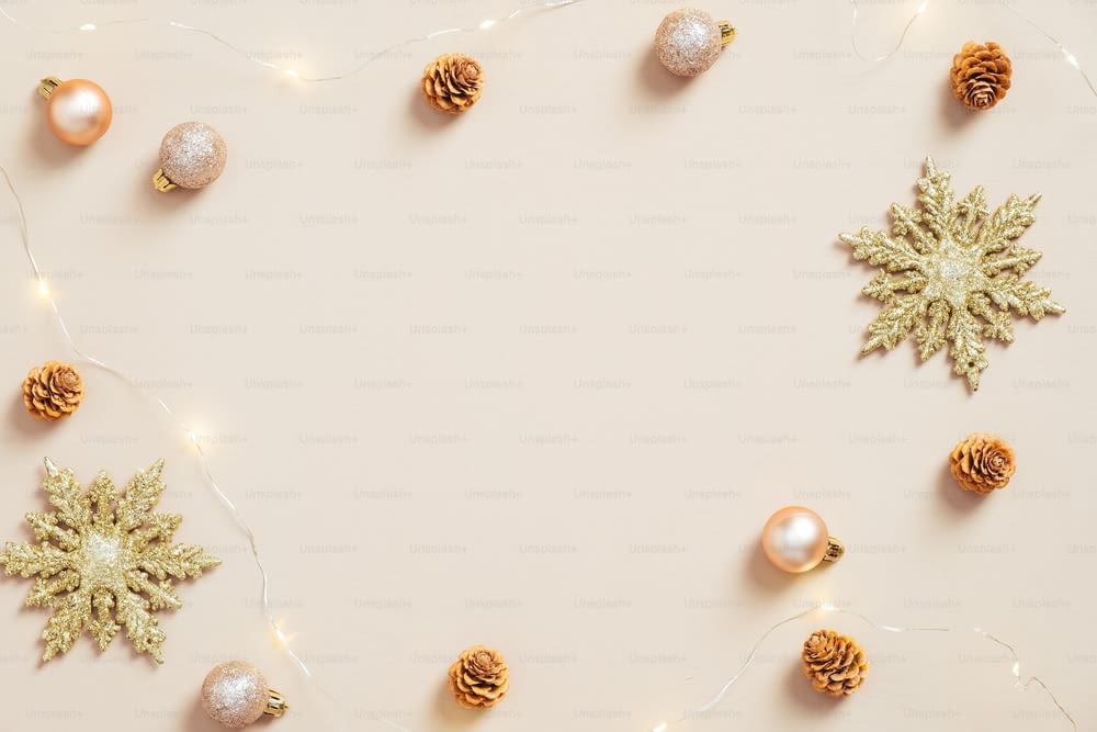 Elegante composición navideña plana. Copos de nieve dorados, bolas, conos, guirnalda sobre fondo beige pastel. Minimalista, estilo nórdico. Maqueta de tarjeta de felicitación navideña.