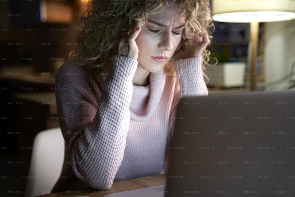 Mujer cansada trabajando en una computadora portátil en el escritorio.
