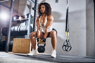 Low angle of a qualified female bodybuilder doing the kettlebell deadlift in a fitness center