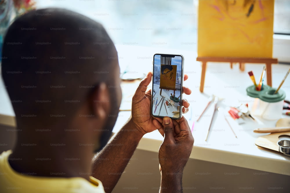 Pessoa tirando uma foto de um desenho e pintando eletrodomésticos em um celular e assistindo ao resultado