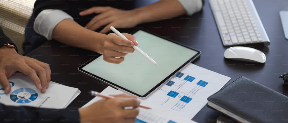 Cropped shot of businesspeople hands working with tablet and business chart on the table