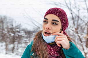 Don't touch your face, stop spreading Coronavirus. Young woman touching her mouth with dirty hand. Avoid touching your face. Woman putting down face mask rubbing her lip outdoor.