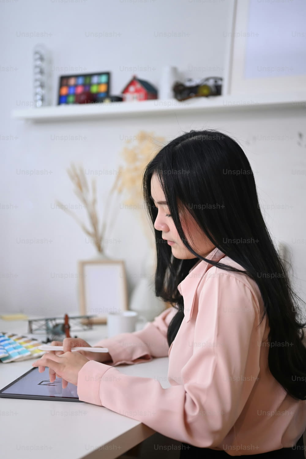 Young woman artist illustrator painting and drawing on digital tablet with stylus.