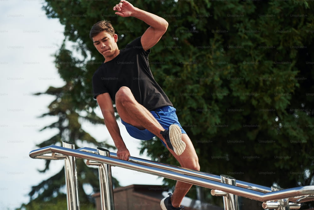 Jumping above obstacle. Young sports man doing parkour in the city at sunny daytime.
