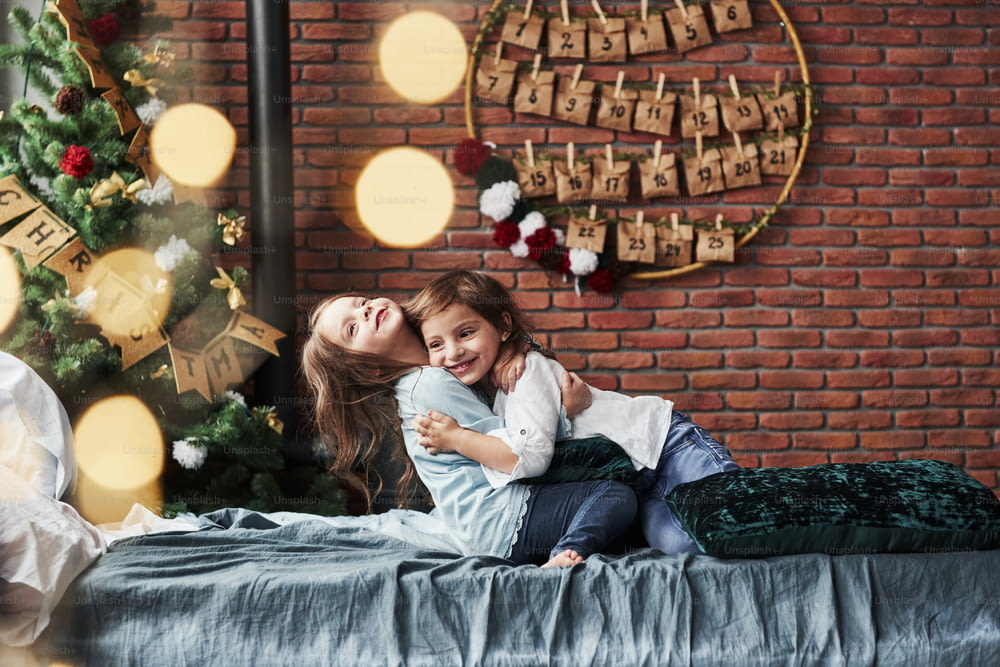 Children finally met each other. Little girls having fun on the bed with holiday interior at the background.