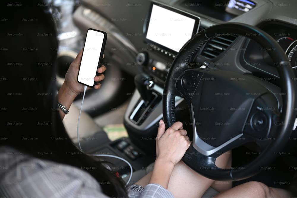 Jeune femme d’affaires assise dans une voiture et utilisant un téléphone portable.