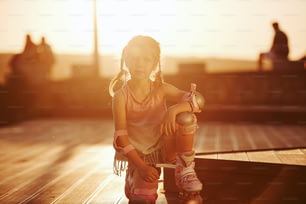 Happy cute kid with her roller skates. Unbelievable sunlight.
