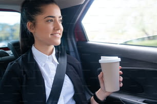 Ritratto di donna d'affari che beve caffè mentre va al lavoro in auto. Concetto di business.