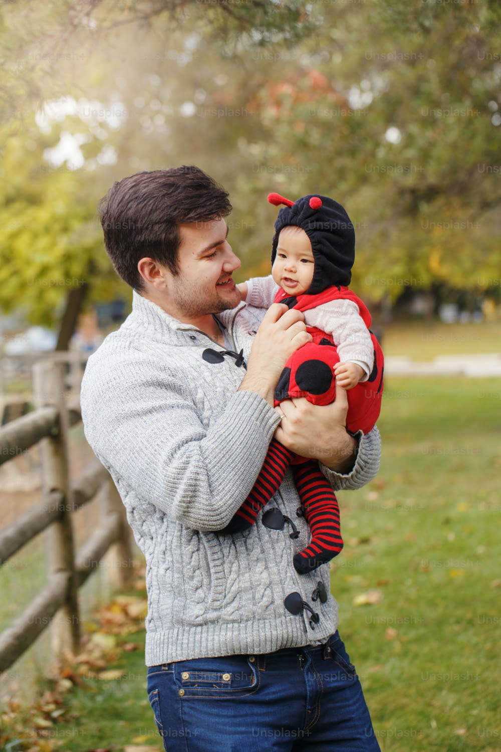 Happy smiling Caucasian father dad with cute adorable baby girl in ladybug costume. Family in autumn fall park outdoor. Halloween seasonal holiday concept. Fathers Day.
