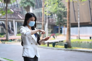 屋外で手を洗い、消毒するためにアルコールスプレーを塗る防護マスク姿の若い女性。