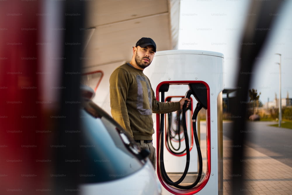 Mann gießt Benzin in sein Auto. Der Mensch steht im Mittelpunkt.  Elektrische Pumpe für Auto.