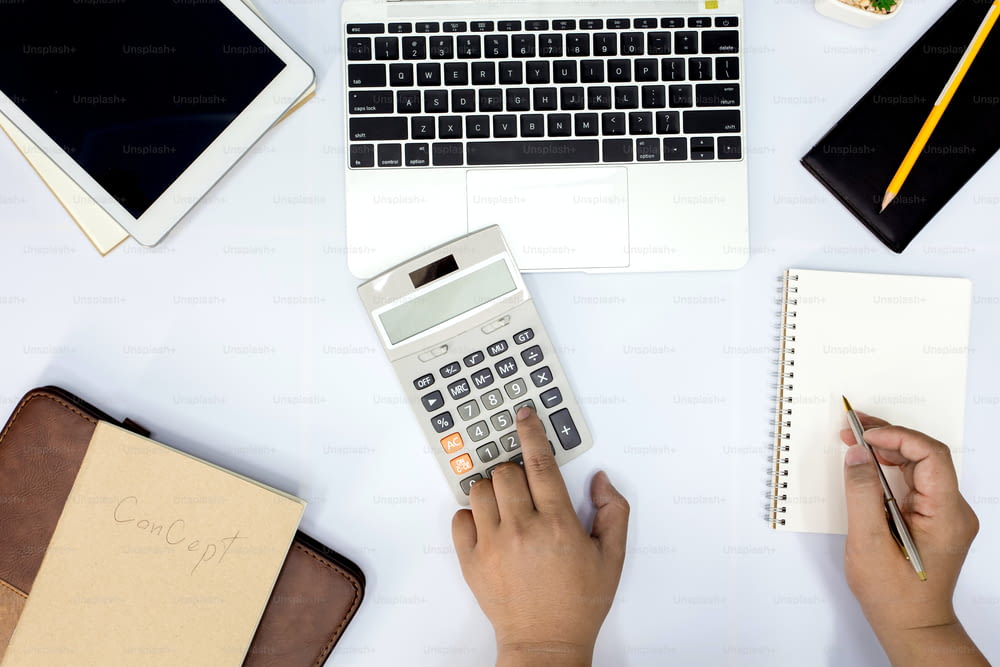 Homem usando calculadora e escrita fazer anotações com cálculo no escritório e Monitoramento de informações financeiras