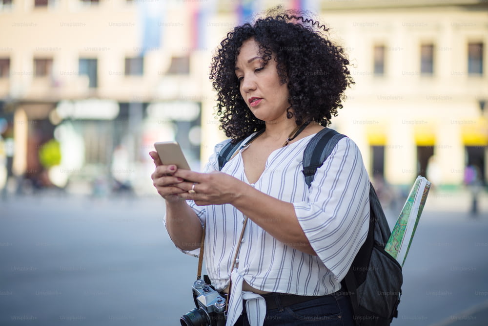 Femme touriste debout dans la rue et utilisant un téléphone intelligent.