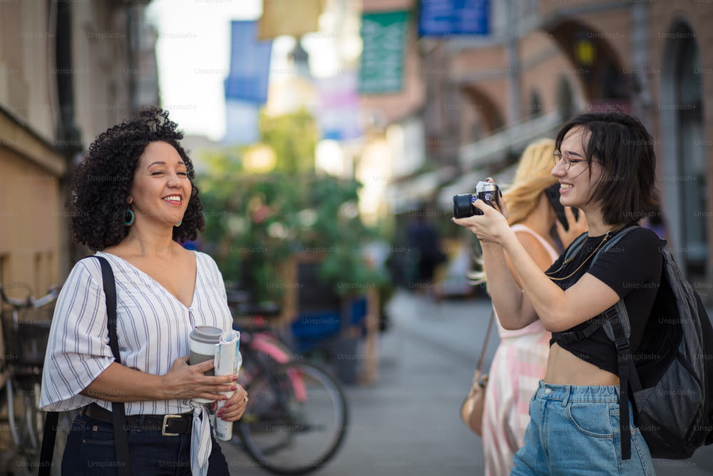 Woman taking photo of her friend. Two tourist women on street.