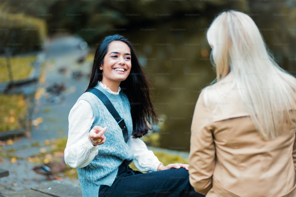 Dos mujeres conversando en el parque. La atención se centra en la mujer sonriente.