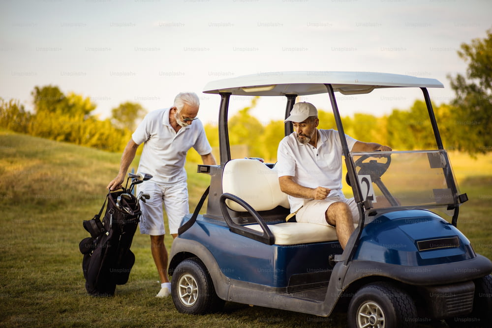 Two senior men golfers on court. Man sitting in golf cart.
