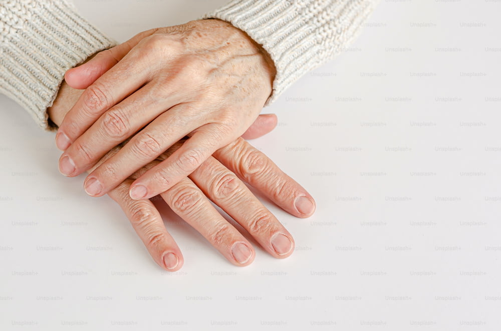 Hands of an elderly woman on white background. Close up, copy space.