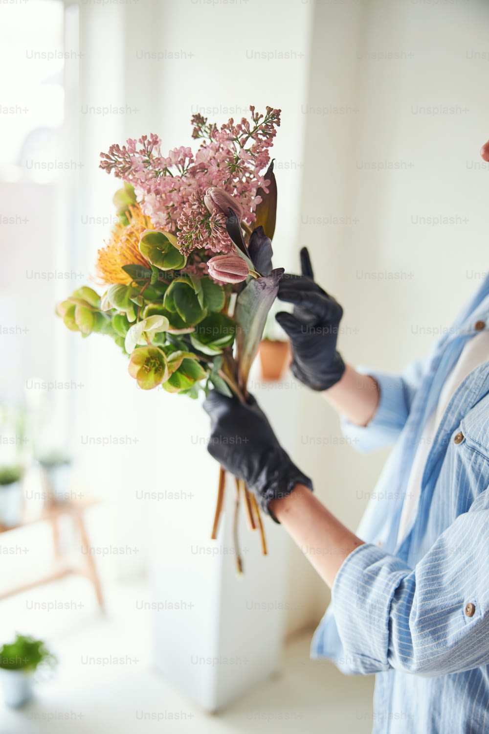Cropped photo of a woman in nitrile gloves holding a bunch of beautiful mixed flowers