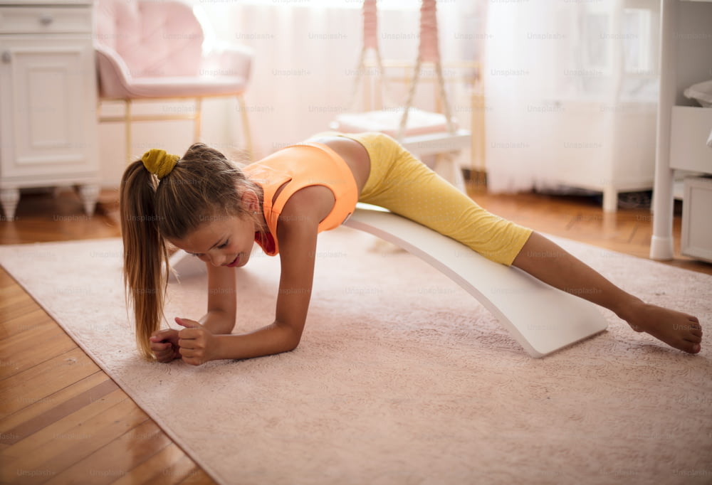 自宅の寝室でトレーニングをしている小さな女の子。
