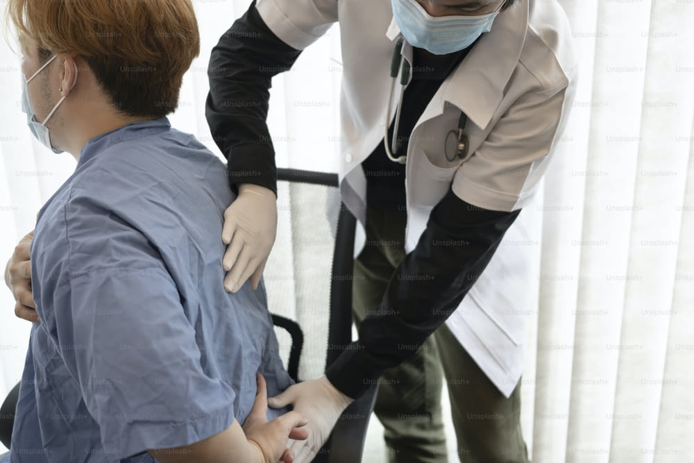 Médecin examinant un patient souffrant de maux de dos.
