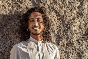 Closeup portrait of smiling handsome italian man with long curly hair. Outdoor photo.