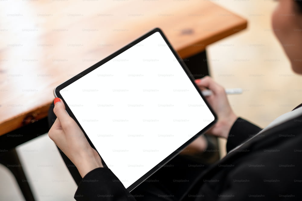 Primer plano de la mujer que trabaja con el lápiz óptico en la tableta digital con la pantalla blanca en blanco.