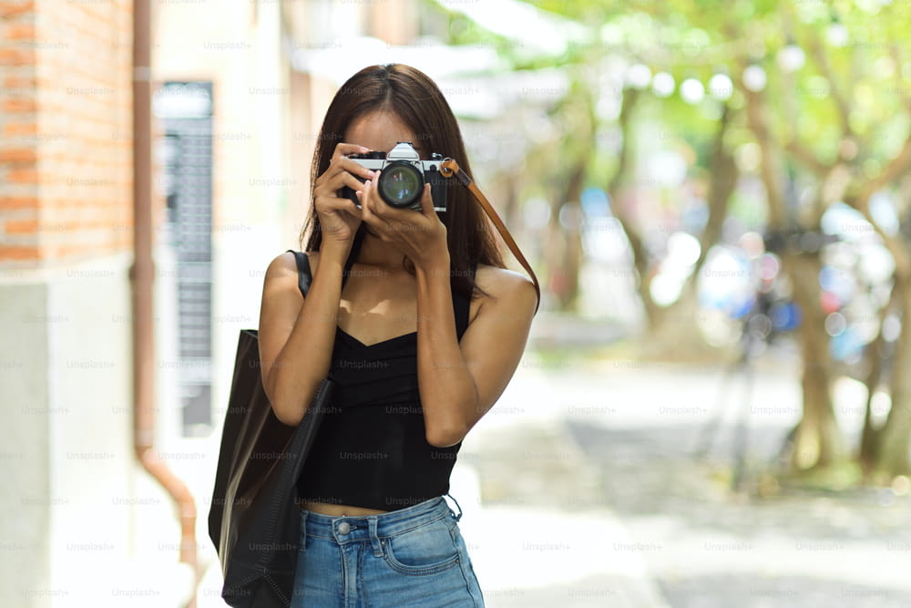 Fotógrafa turística feminina tirando foto da cidade velha com câmera vintage, capturando o feriado, hobby hipster e atividade