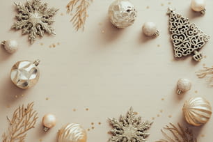 Fond de Noël élégant. Cadre bordé de décorations dorées, boules, confettis sur table beige. Mise à plat, vue de dessus, espace de copie. Conception de bannière de Noël, maquette de carte de voeux du Nouvel An.