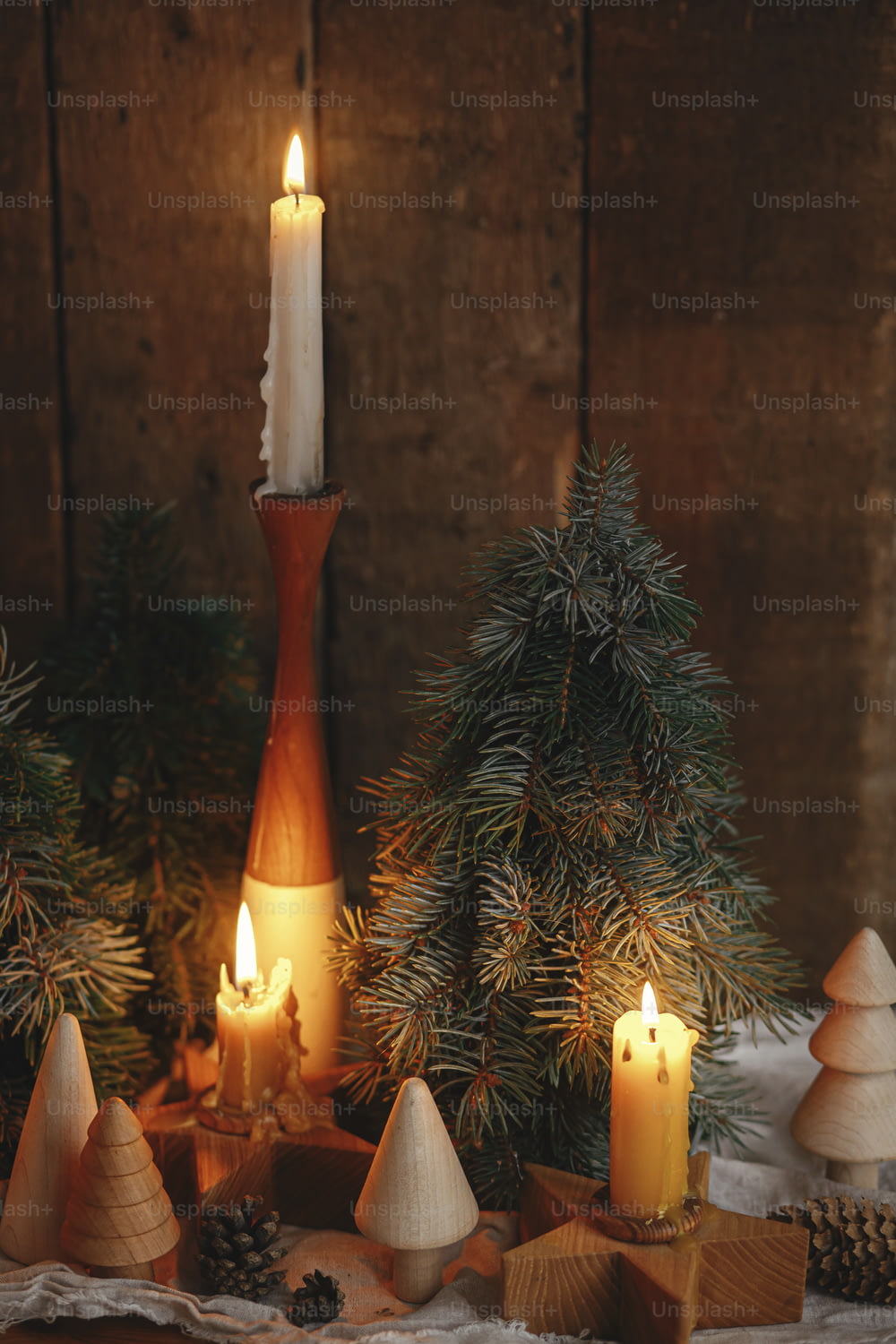 Christmas advent. Stylish burning christmas candles, pine trees and cones modern decorations on rustic old wooden background in evening scandinavian room. Atmospheric moment