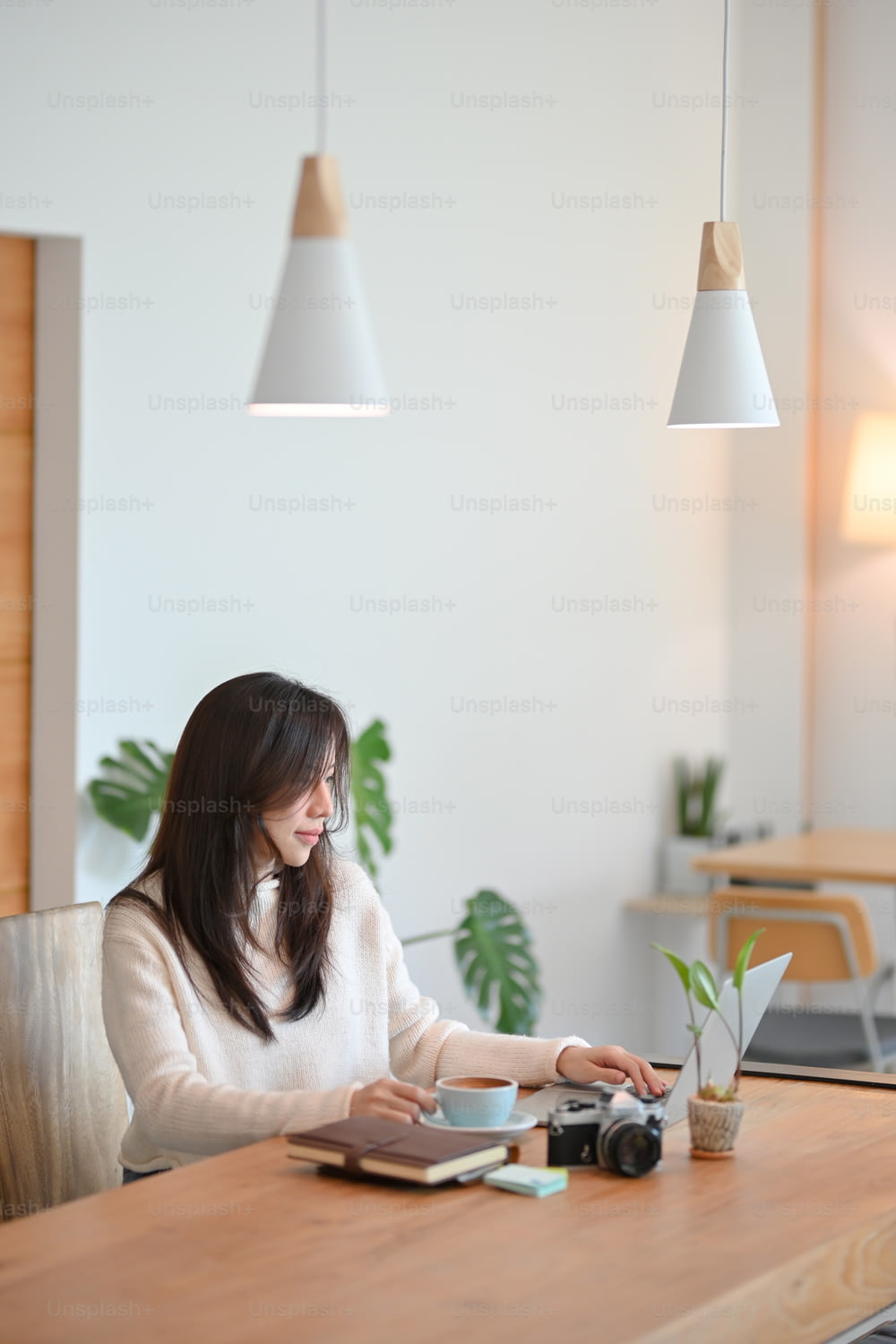 Affascinante giovane donna asiatica cafe o blogger di viaggio che lavora sul suo computer portatile in un moderno caffè elegante