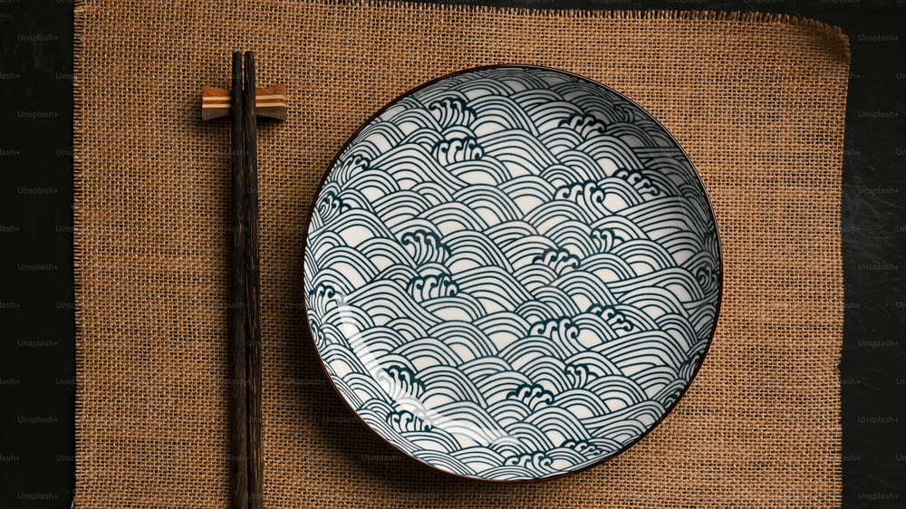 Asian crockery concept, ceramic plate with chopsticks on brown placemat. porcelain, blue and white dish. top view