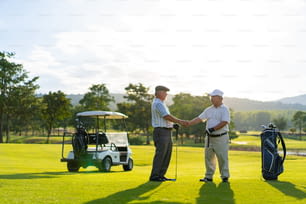 Asiáticos, empresarios, CEO senior estrechando la mano después de terminar de hablar sobre el proyecto de negocios y jugar al golf juntos en el campo de golf. Los amigos golfistas mayores disfrutan del deporte al aire libre jugando al golf juntos en el club de campo.