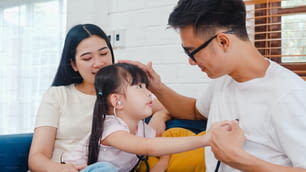 Papa de famille asiatique heureux et joyeux, maman et fille jouant à un jeu amusant en tant que médecin s’amusant sur le canapé à la maison.