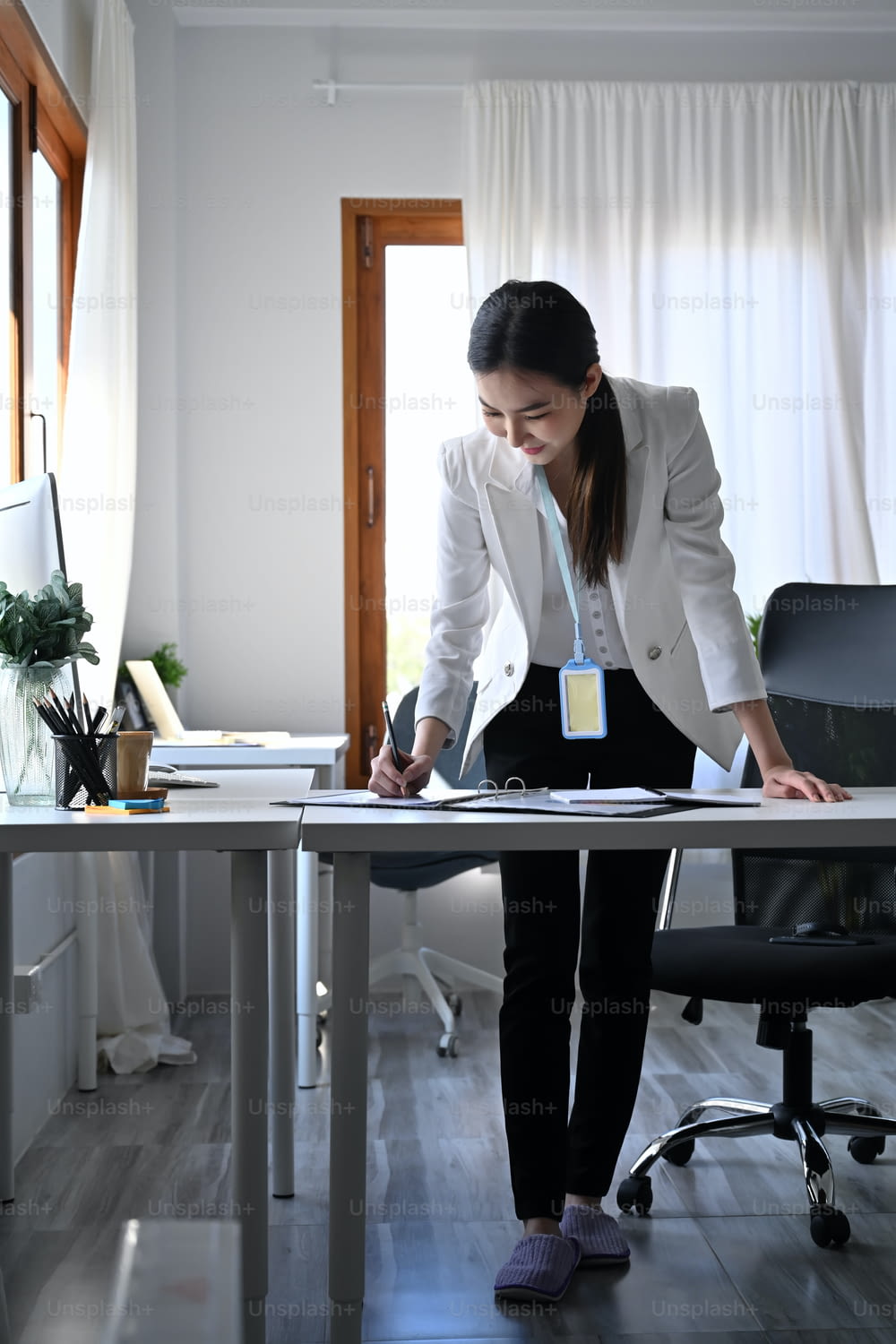 Portrait en pied d’une femme d’affaires debout sur son lieu de travail et signant un document d’affaires.