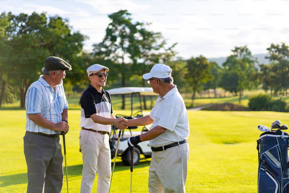 4K Group de personas asiáticas, hombre de negocios y director ejecutivo senior disfrutan del estilo de vida deportivo al aire libre jugando al golf juntos en el club de campo de golf. Golfista de hombres sanos que se dan la mano después de terminar el juego en el campo de golf en las vacaciones de verano