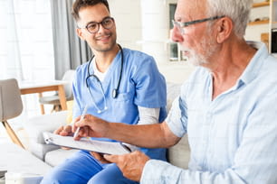 Infermiere maschio che parla con pazienti anziani durante una visita domiciliare.