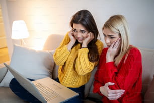 Moças assustadas assistindo filme em casa. Meninas assistindo a um filme de terror assustador na TV sentados em um sofá em casa