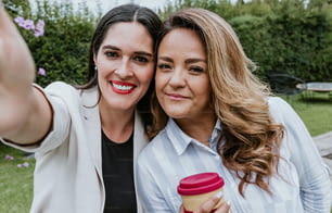 Zwei lateinamerikanische Geschäftsfrauen beim Foto-Selfie mit Handy im Terrassenbüro in Mexiko Lateinamerika