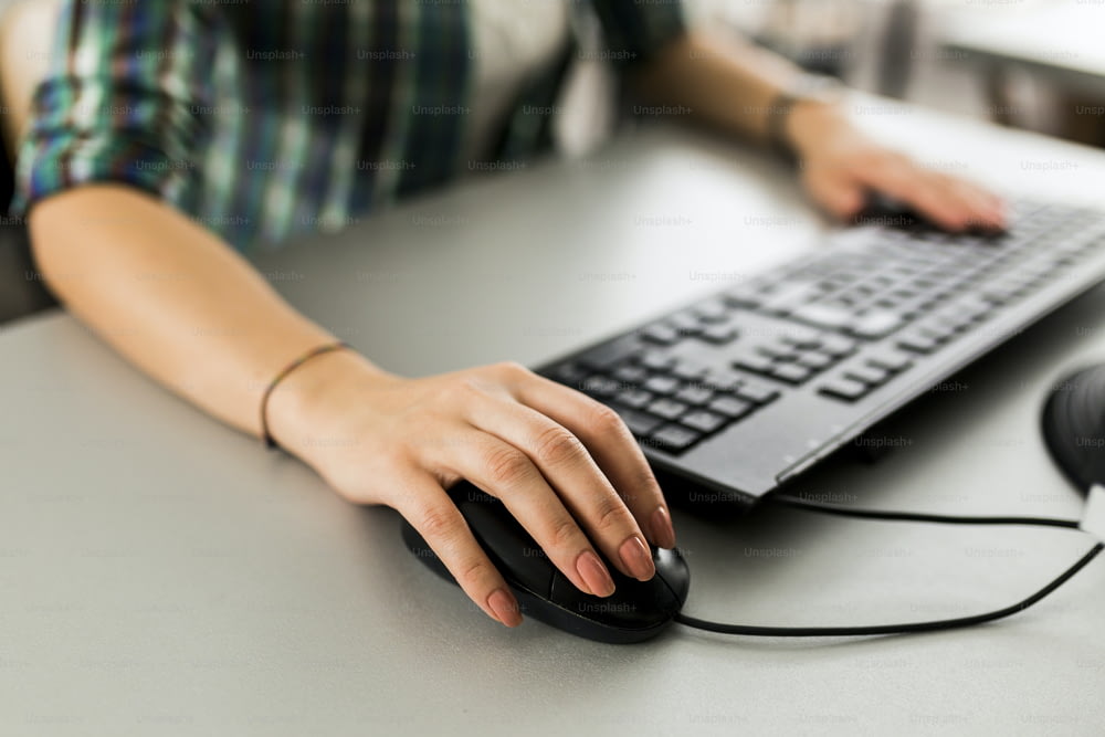Close up de uma mulher usando um teclado de computador e um mouse