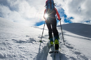 Bergsteigerin klettert auf Skiern und Robbenfellen der Sonne entgegen