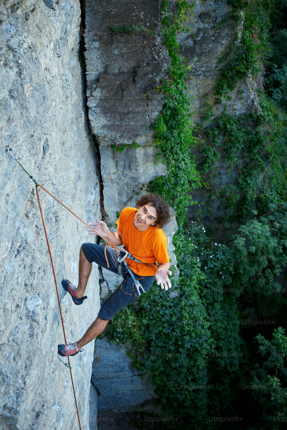 Männlicher Kletterer. Kletterer klettert auf eine Felswand. Mann ruht an einem Seil