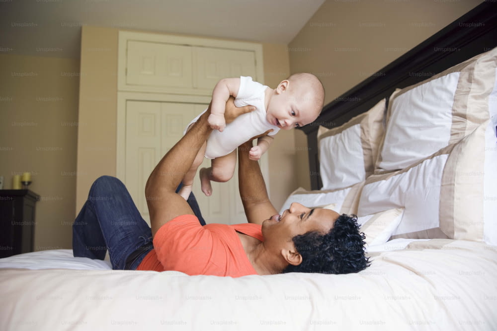 a man holding a baby in his arms on a bed