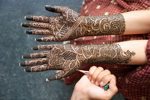 Eine Frau mit Henna an den Händen, die einen Bleistift hält