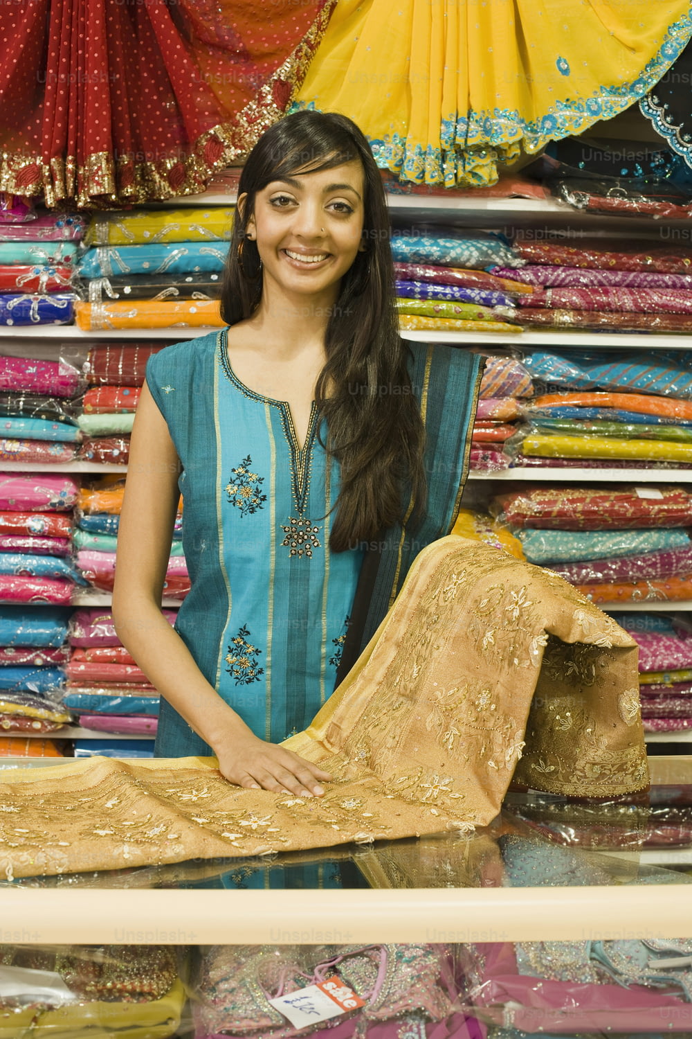 a woman standing in front of a display of saris