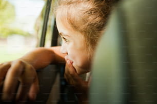 Una niña asomada por la ventanilla de un coche