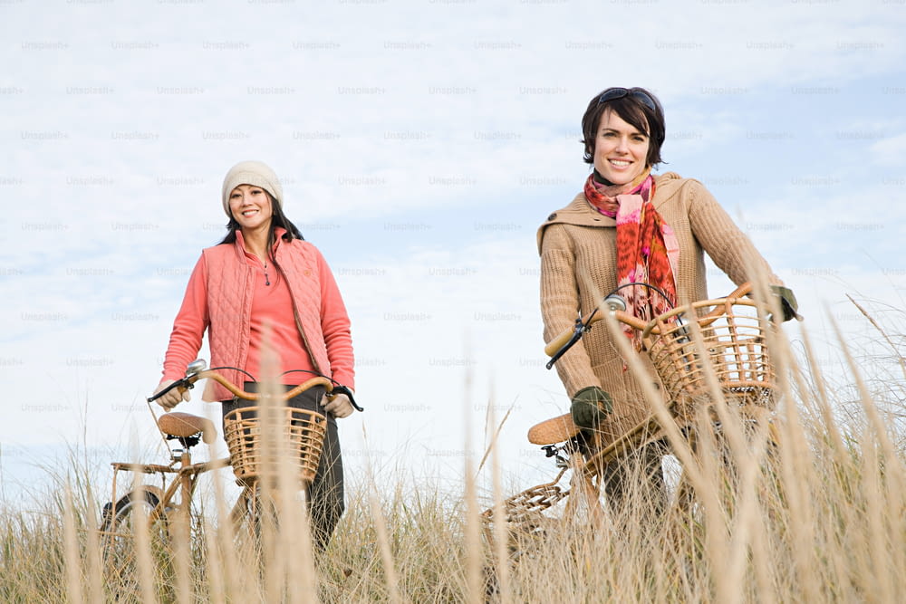 um casal de mulheres andando de bicicleta por um campo coberto de grama