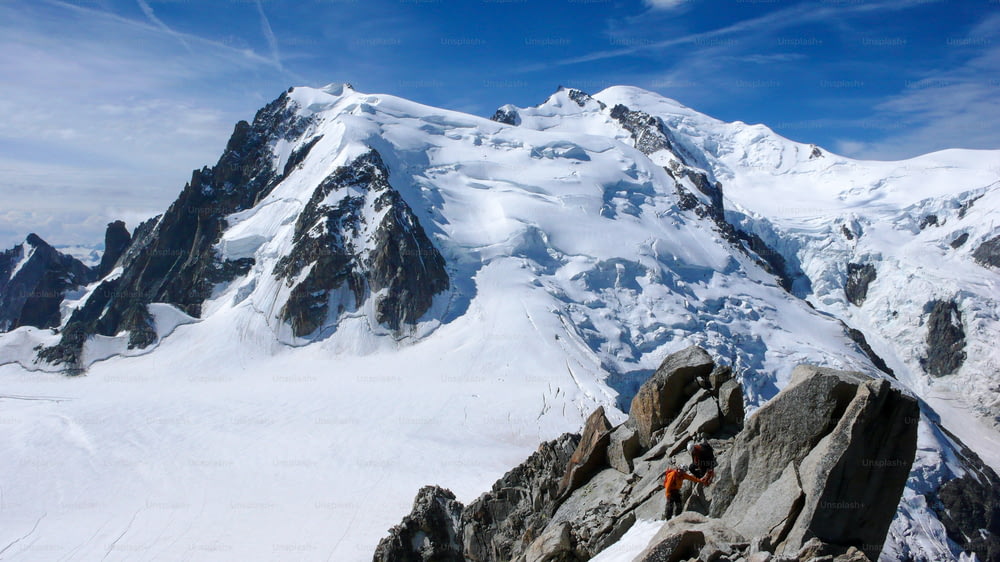 シャモニー近郊のフレンチアルプスの高峰に向かう岩と雪の尾根にいる山岳ガイドと男性客