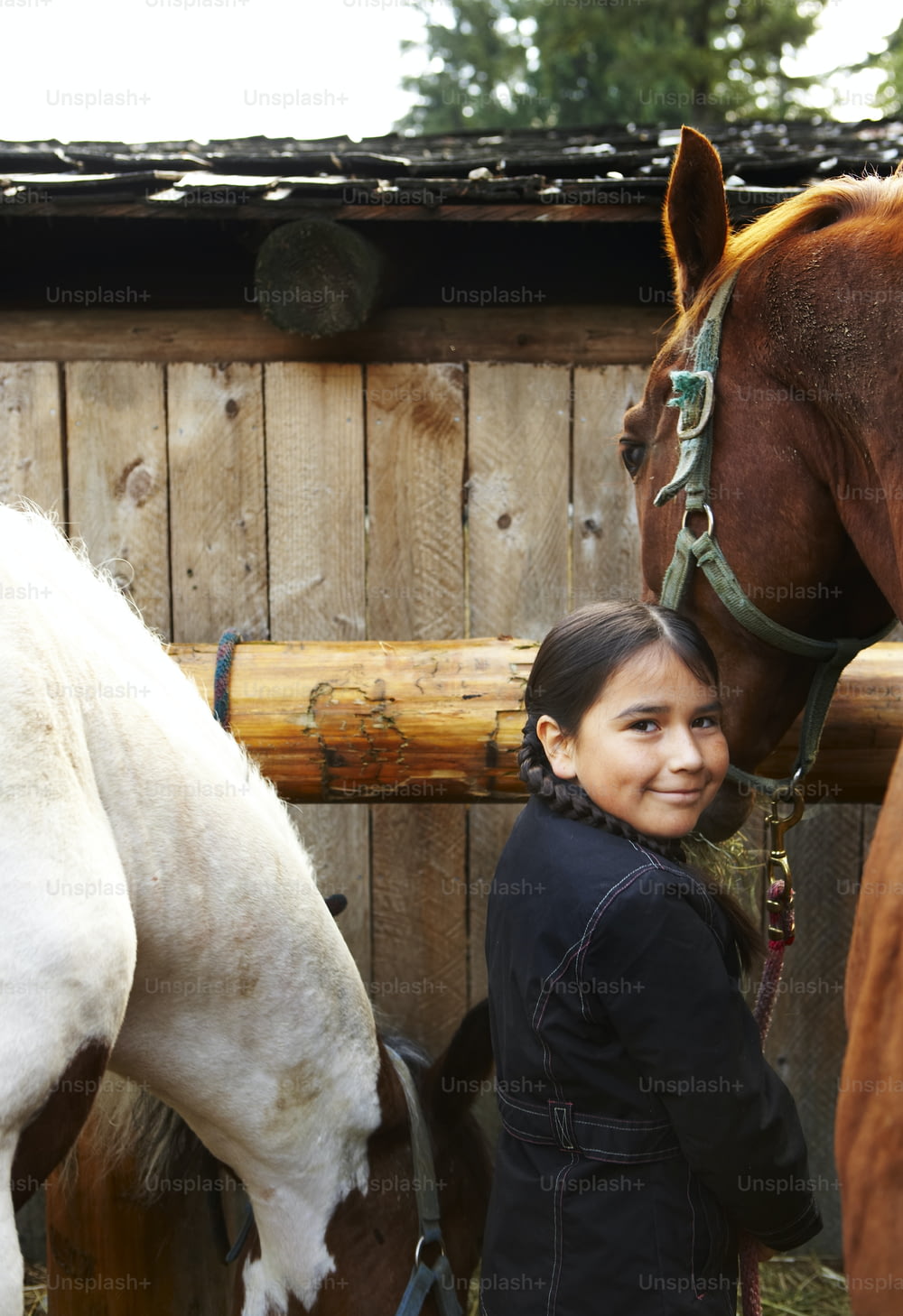 a young girl standing next to a brown and white horse